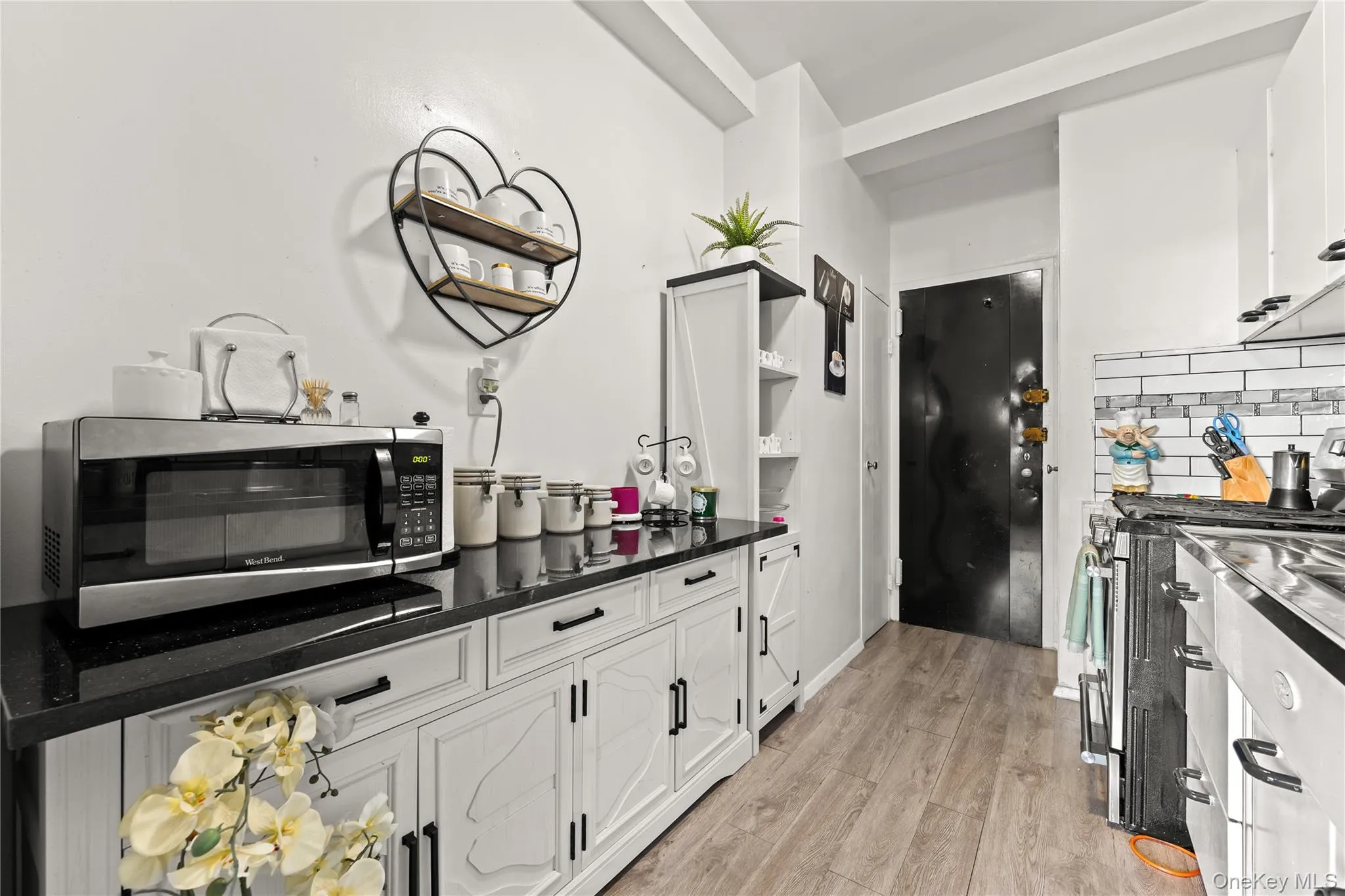 Kitchen with open shelves, white cabinets, tasteful backsplash, and appliances with stainless steel finishes Kitchen with open shelves, white cabinets, tasteful backsplash, and appliances with stainless steel finishes