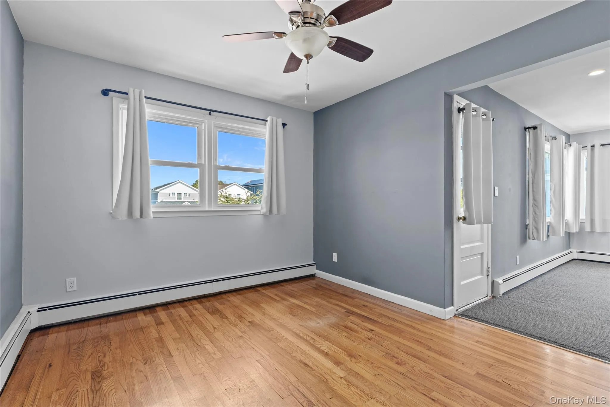Spare room with baseboard heating, light wood-style flooring, and a ceiling fan Spare room with baseboard heating, light wood-style flooring, and a ceiling fan