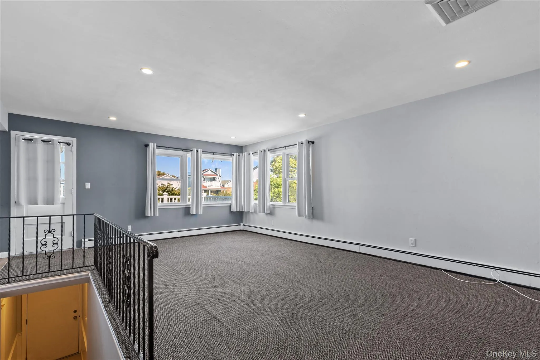 Carpeted empty room featuring recessed lighting and a baseboard radiator Carpeted empty room featuring recessed lighting and a baseboard radiator
