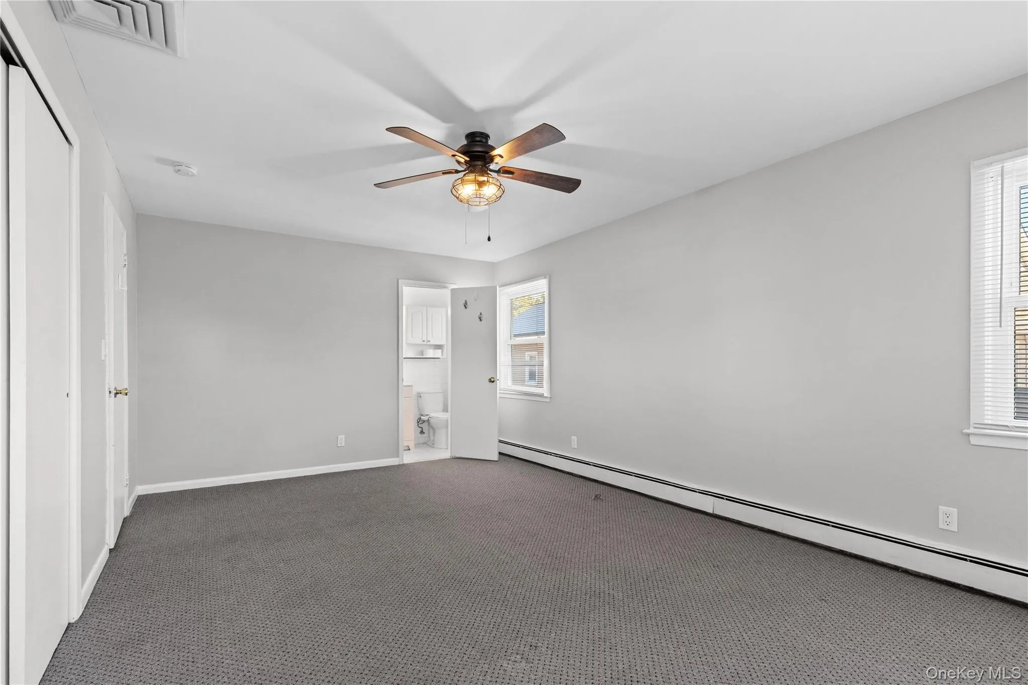 Unfurnished room featuring baseboard heating, carpet, and ceiling fan Unfurnished room featuring baseboard heating, carpet, and ceiling fan