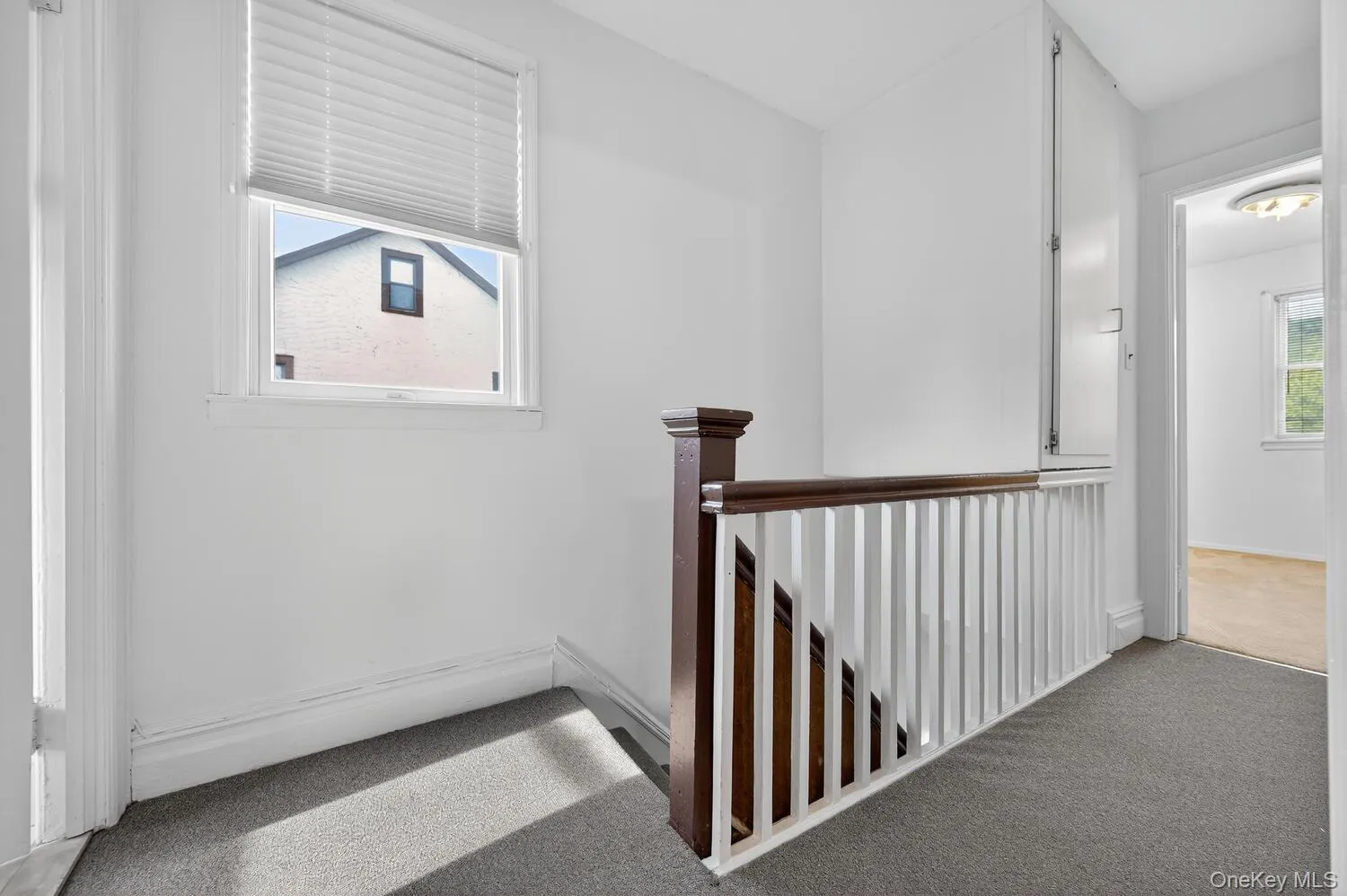 Hallway with an upstairs landing and carpet Hallway with an upstairs landing and carpet