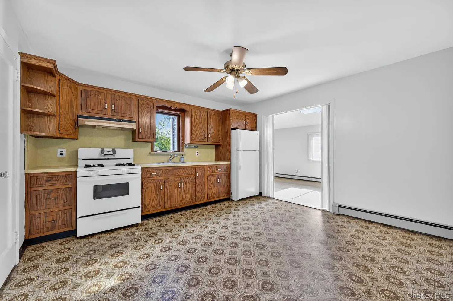 Kitchen with light countertops, white appliances, brown cabinetry, open shelves, and under cabinet range hood Kitchen with light countertops, white appliances, brown cabinetry, open shelves, and under cabinet range hood