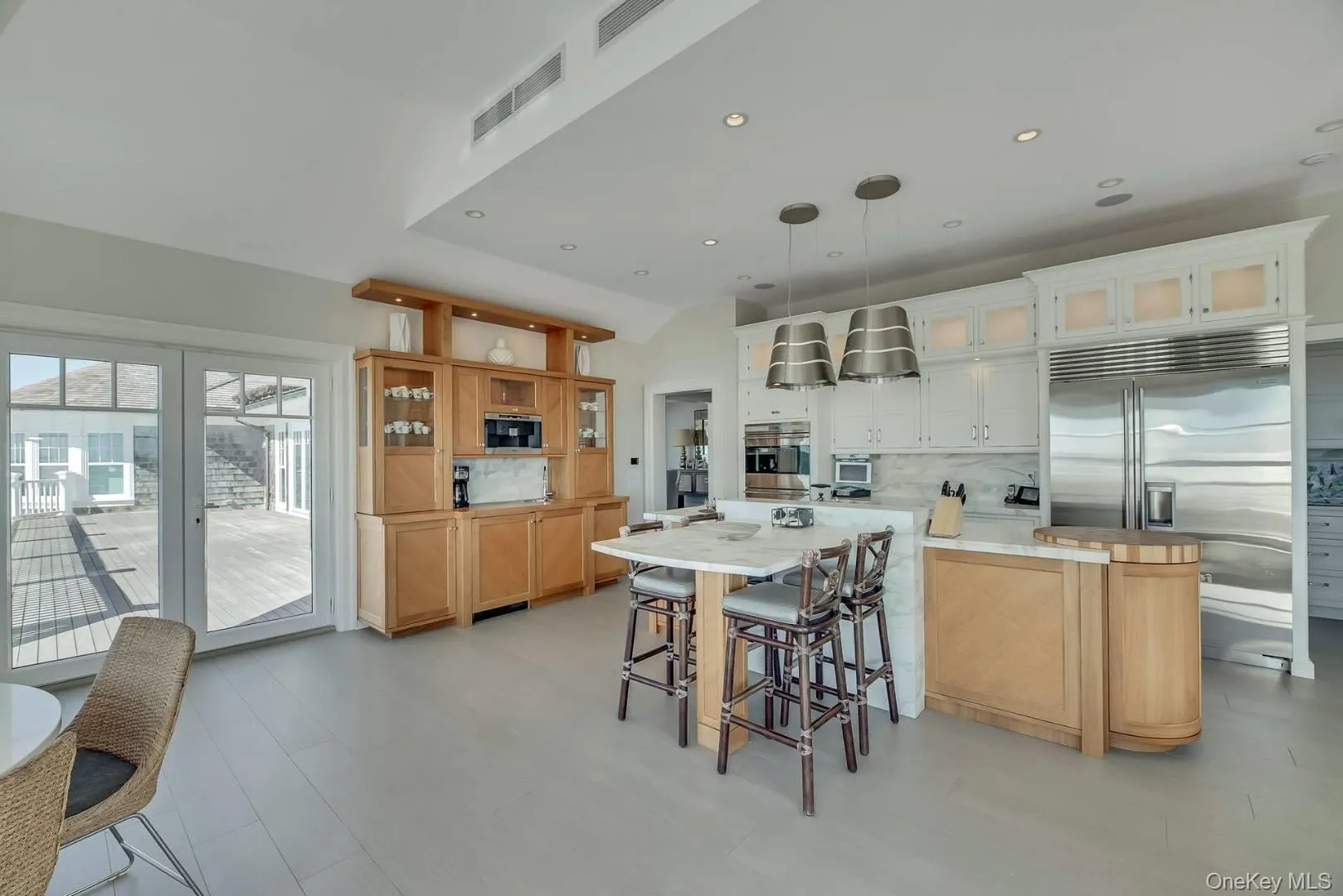 Kitchen with a kitchen bar, glass insert cabinets, decorative backsplash, decorative light fixtures, and built in appliances Kitchen with a kitchen bar, glass insert cabinets, decorative backsplash, decorative light fixtures, and built in appliances