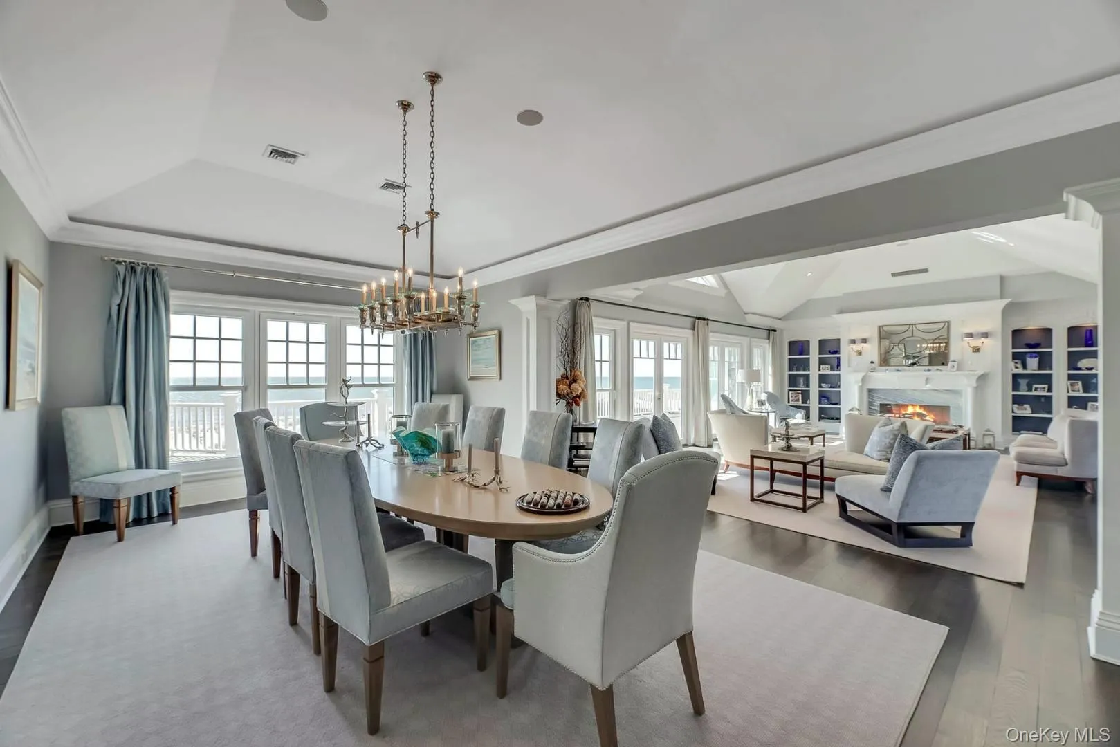 Dining area featuring a lit fireplace, a tray ceiling, crown molding, and plenty of natural light Dining area featuring a lit fireplace, a tray ceiling, crown molding, and plenty of natural light