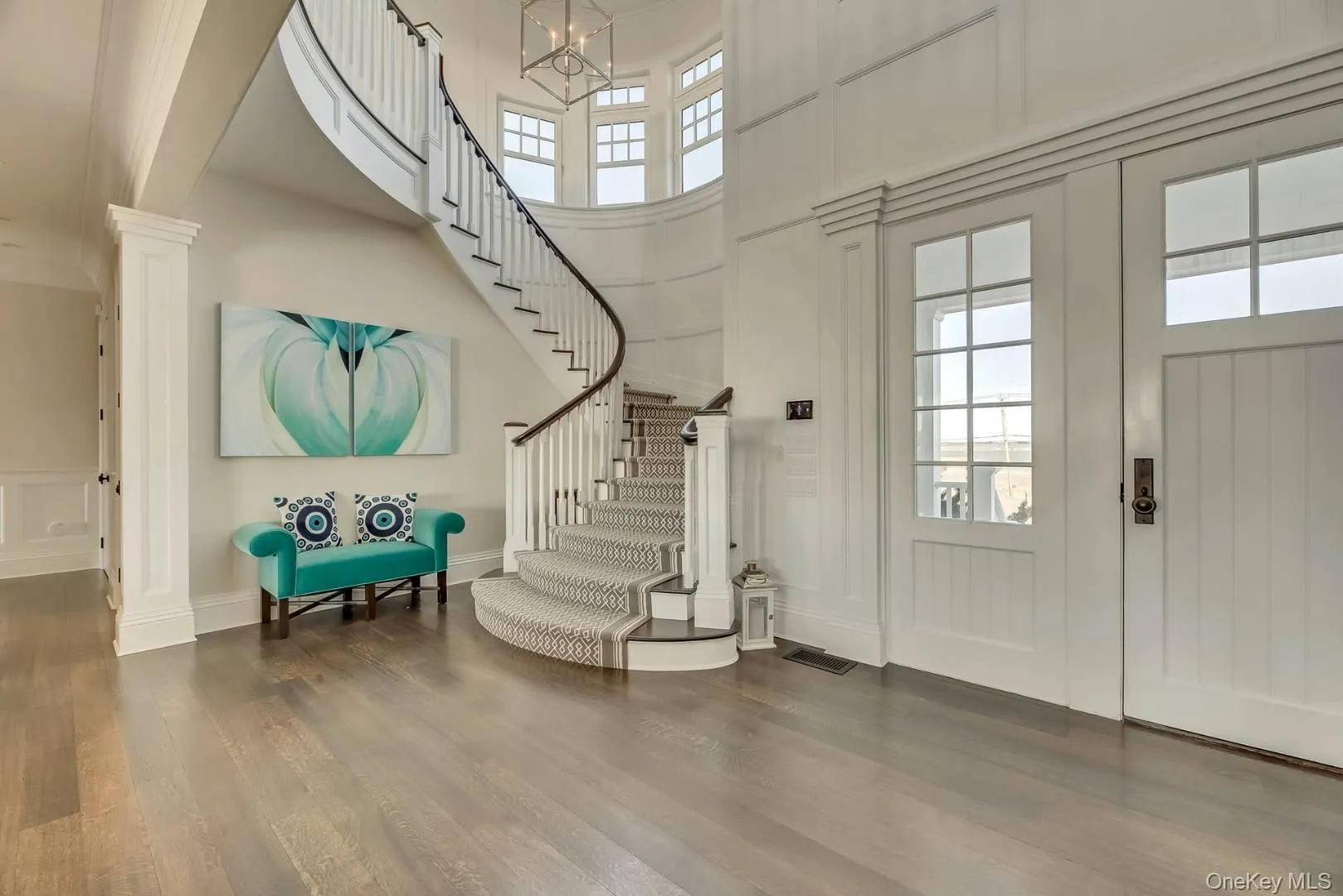 Entryway featuring plenty of natural light, a high ceiling, wood finished floors, a decorative wall, and stairway Entryway featuring plenty of natural light, a high ceiling, wood finished floors, a decorative wall, and stairway