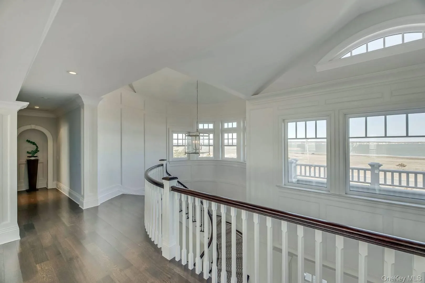 Hall featuring healthy amount of natural light, ornamental molding, dark wood-type flooring, vaulted ceiling, and recessed lighting Hall featuring healthy amount of natural light, ornamental molding, dark wood-type flooring, vaulted ceiling, and recessed lighting
