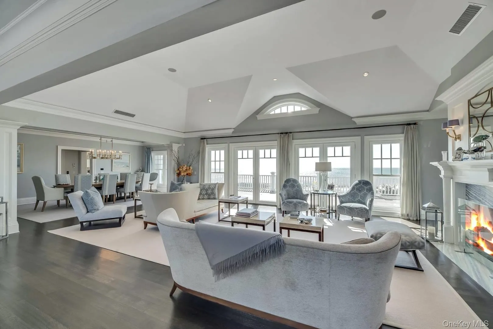 Living room featuring ornamental molding, wood finished floors, a premium fireplace, a chandelier, and lofted ceiling Living room featuring ornamental molding, wood finished floors, a premium fireplace, a chandelier, and lofted ceiling