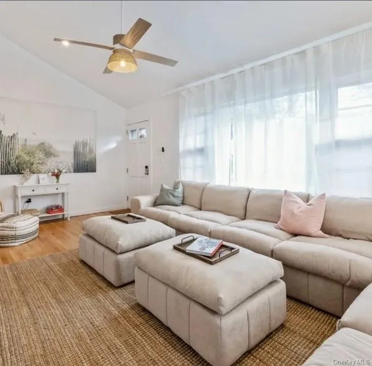 Living room with plenty of natural light, lofted ceiling, ceiling fan, and wood finished floors Living room with plenty of natural light, lofted ceiling, ceiling fan, and wood finished floors