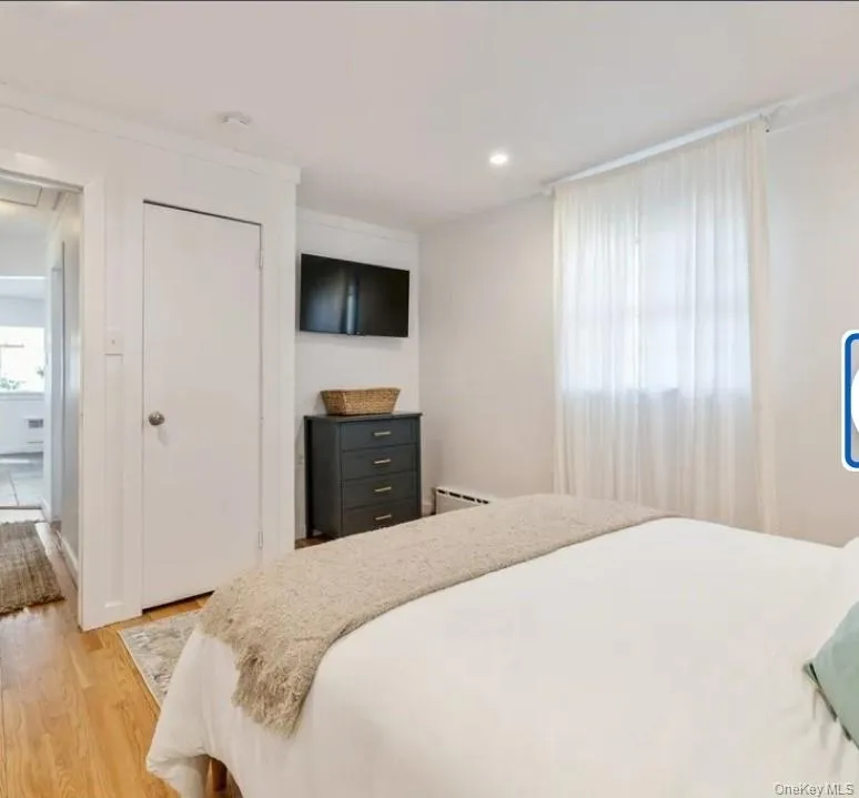 Bedroom with light wood finished floors, a closet, a baseboard radiator, recessed lighting, and ornamental molding Bedroom with light wood finished floors, a closet, a baseboard radiator, recessed lighting, and ornamental molding