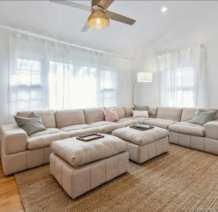 Living room featuring plenty of natural light, lofted ceiling, a ceiling fan, and light wood finished floors Living room featuring plenty of natural light, lofted ceiling, a ceiling fan, and light wood finished floors