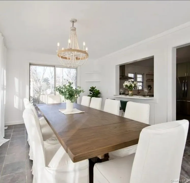 Dining space featuring dark tile patterned flooring and a chandelier Dining space featuring dark tile patterned flooring and a chandelier