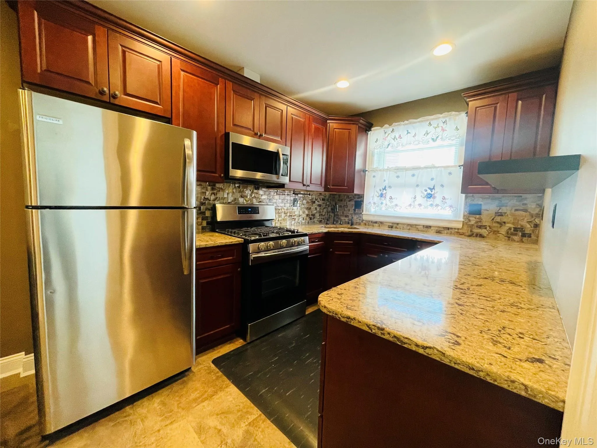 Kitchen with stainless steel appliances, decorative backsplash, light stone countertops, recessed lighting, and dark brown cabinets Kitchen with stainless steel appliances, decorative backsplash, light stone countertops, recessed lighting, and dark brown cabinets