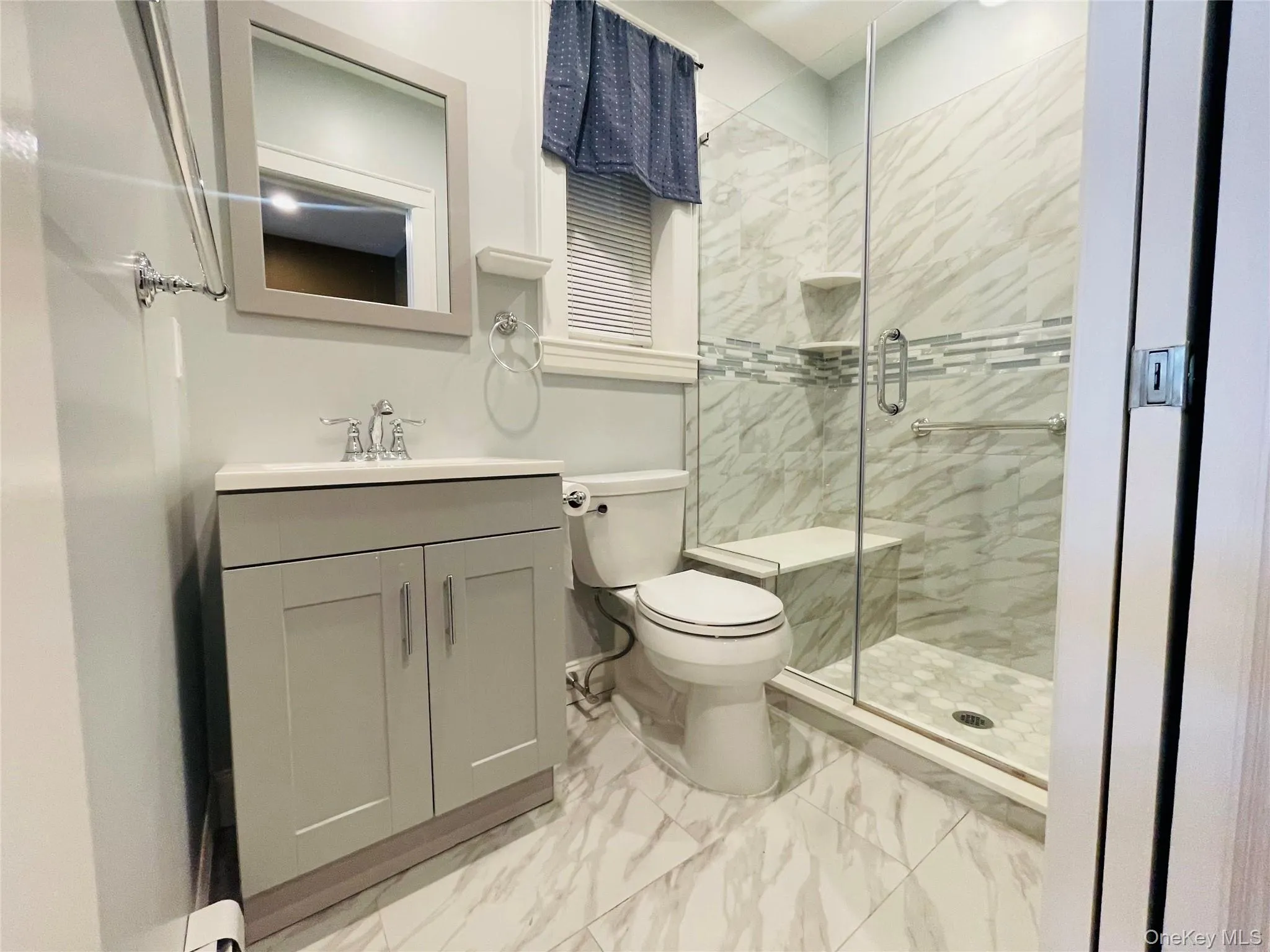 Bathroom with light marble finish flooring, a stall shower, and vanity Bathroom with light marble finish flooring, a stall shower, and vanity