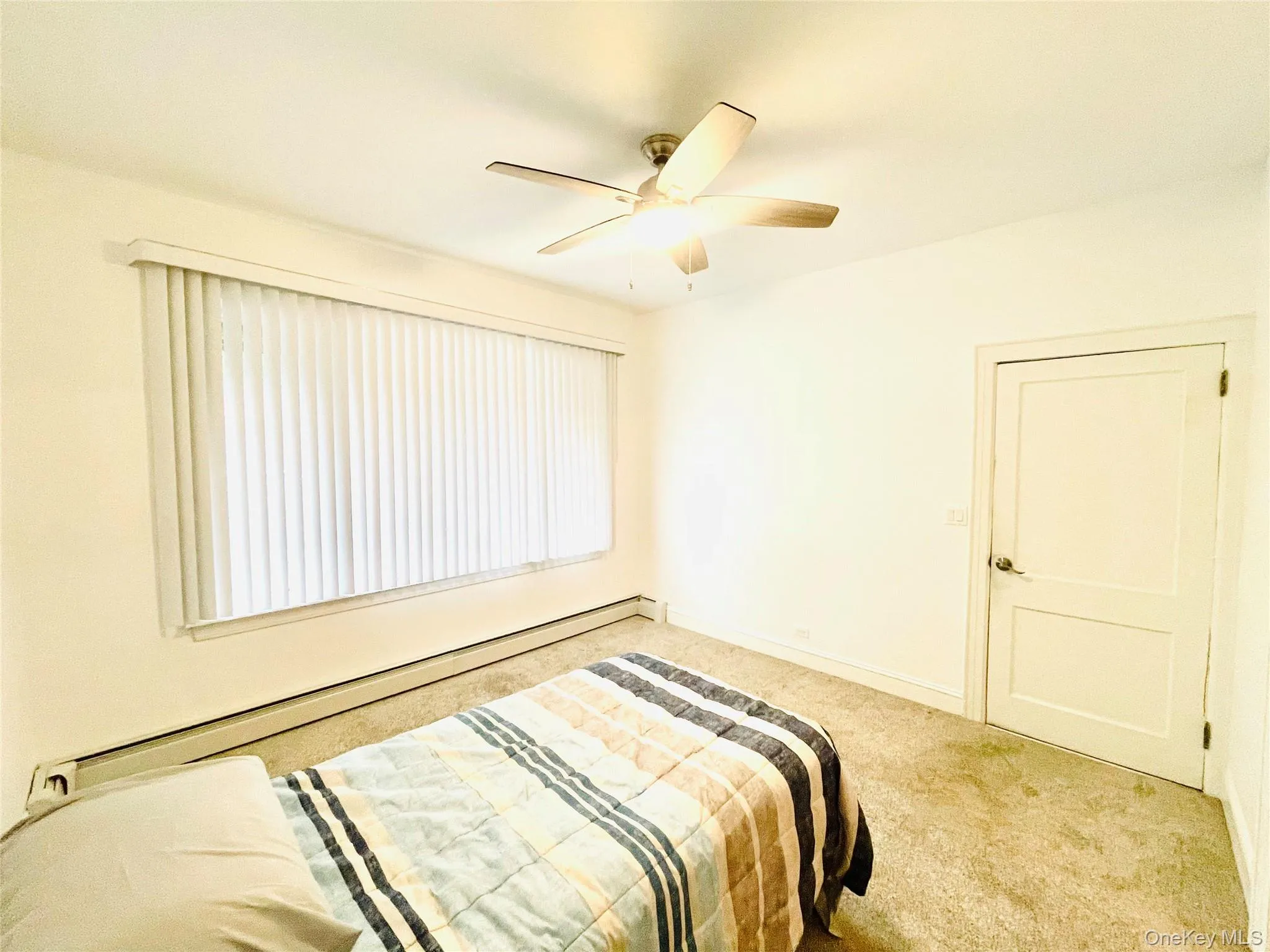 Carpeted bedroom featuring baseboard heating and a ceiling fan Carpeted bedroom featuring baseboard heating and a ceiling fan