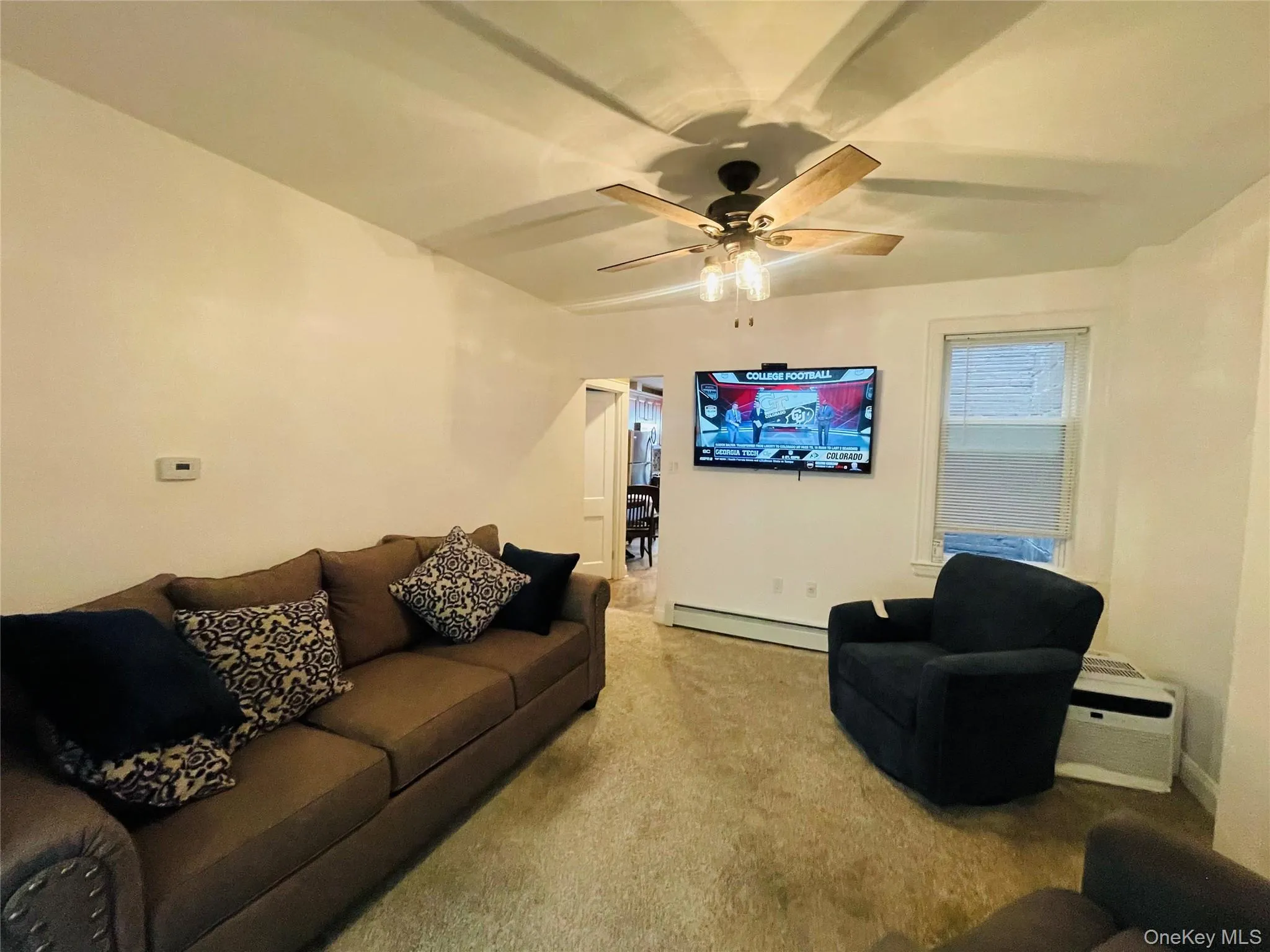 Living room featuring carpet flooring, a baseboard radiator, and a ceiling fan Living room featuring carpet flooring, a baseboard radiator, and a ceiling fan