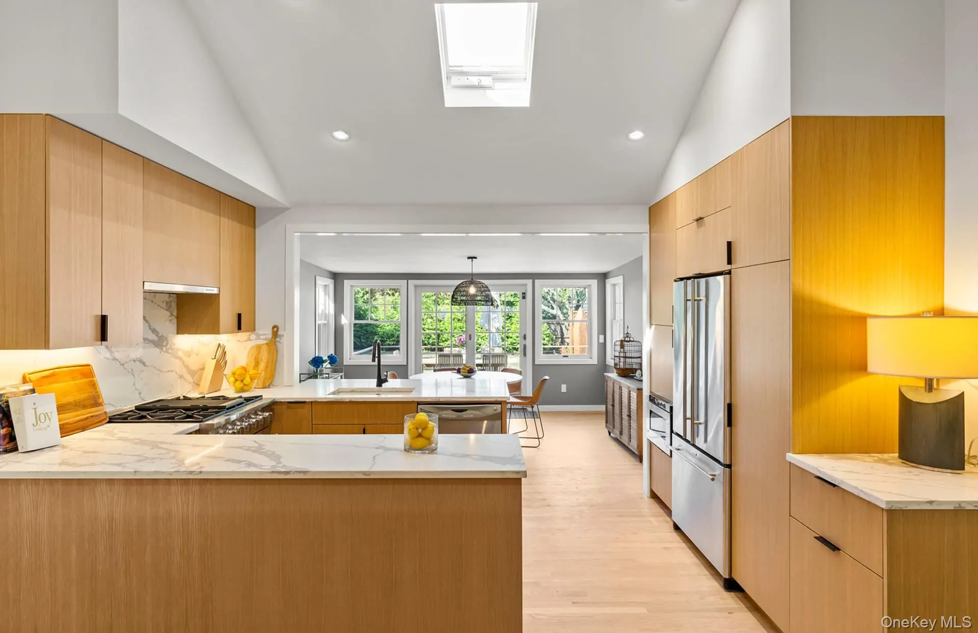 Kitchen featuring light stone counters, light brown cabinets, a peninsula, tasteful backsplash, and lofted ceiling Kitchen featuring light stone counters, light brown cabinets, a peninsula, tasteful backsplash, and lofted ceiling