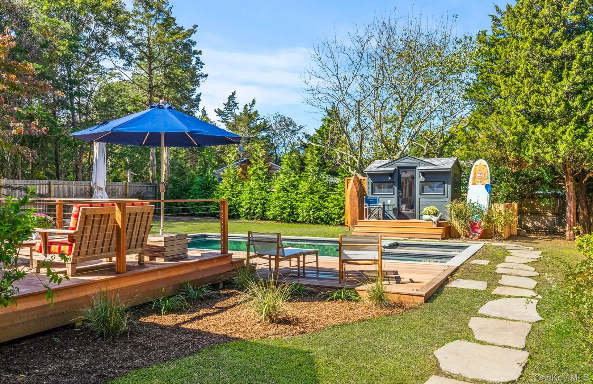 View of jungle gym with a wooden deck, an outbuilding, an outdoor pool, and view of wooded area View of jungle gym with a wooden deck, an outbuilding, an outdoor pool, and view of wooded area