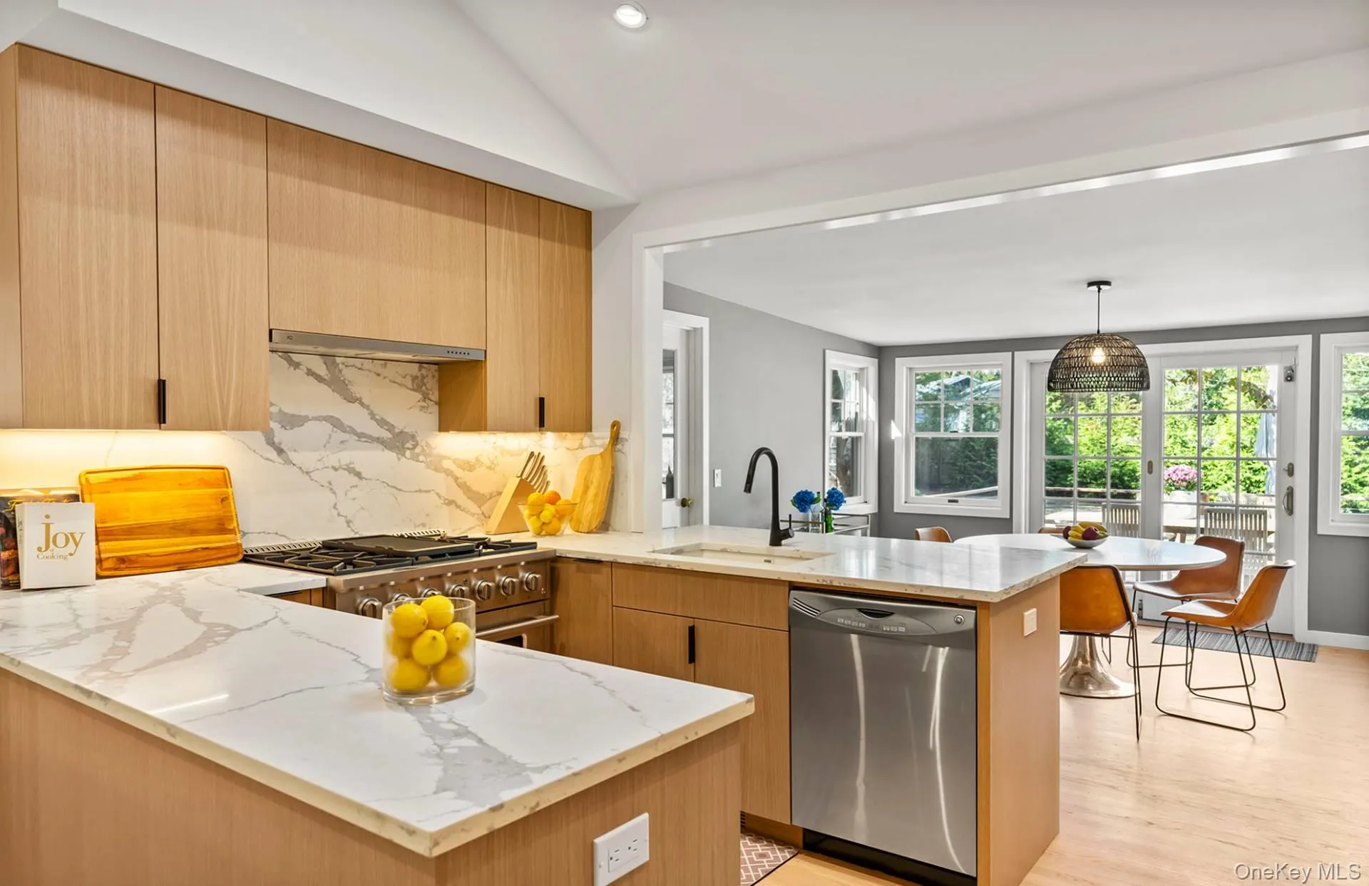 Kitchen with a peninsula, light stone countertops, backsplash, stainless steel appliances, and light wood-style floors Kitchen with a peninsula, light stone countertops, backsplash, stainless steel appliances, and light wood-style floors