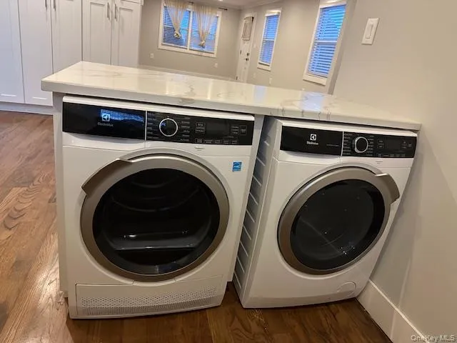 Laundry area with dark wood-style floors and washing machine and clothes dryer Laundry area with dark wood-style floors and washing machine and clothes dryer