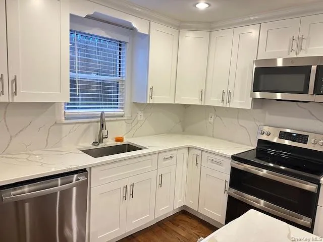 Kitchen featuring appliances with stainless steel finishes, light stone counters, white cabinets, and decorative backsplash Kitchen featuring appliances with stainless steel finishes, light stone counters, white cabinets, and decorative backsplash