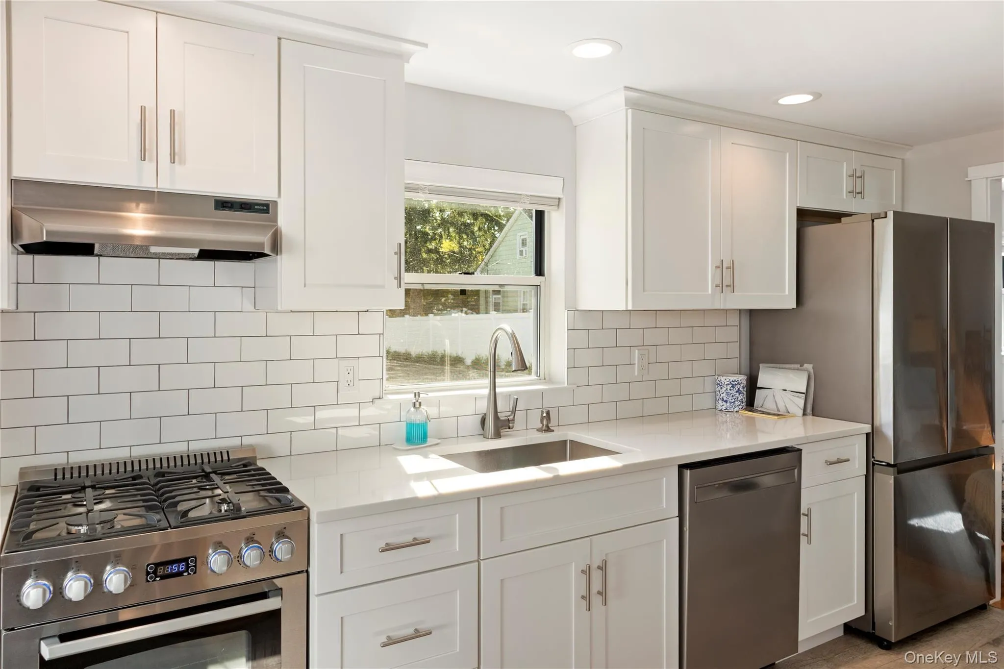 Kitchen featuring appliances with stainless steel finishes, white cabinetry, under cabinet range hood, light stone countertops, and recessed lighting Kitchen featuring appliances with stainless steel finishes, white cabinetry, under cabinet range hood, light stone countertops, and recessed lighting