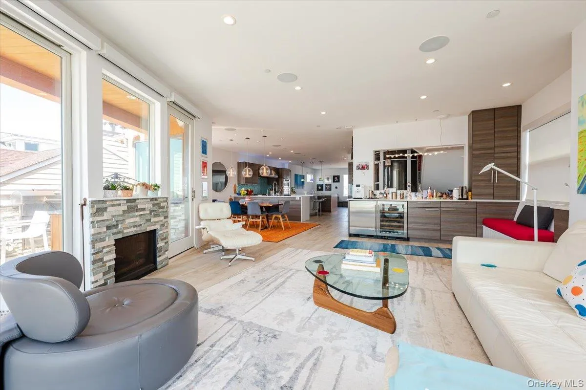 Living room with recessed lighting, a stone fireplace, light wood-type flooring, and beverage cooler Living room with recessed lighting, a stone fireplace, light wood-type flooring, and beverage cooler
