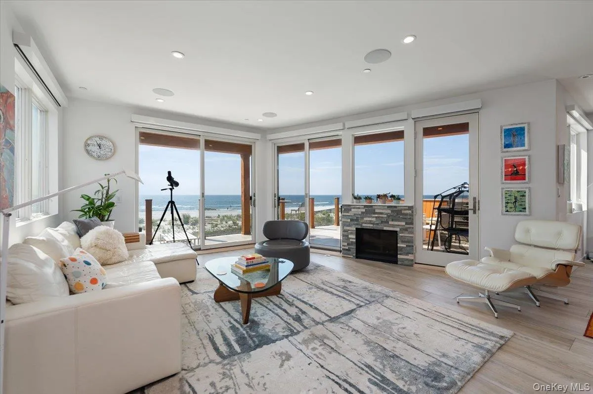 Living room with a water view, wood finished floors, a stone fireplace, and recessed lighting Living room with a water view, wood finished floors, a stone fireplace, and recessed lighting