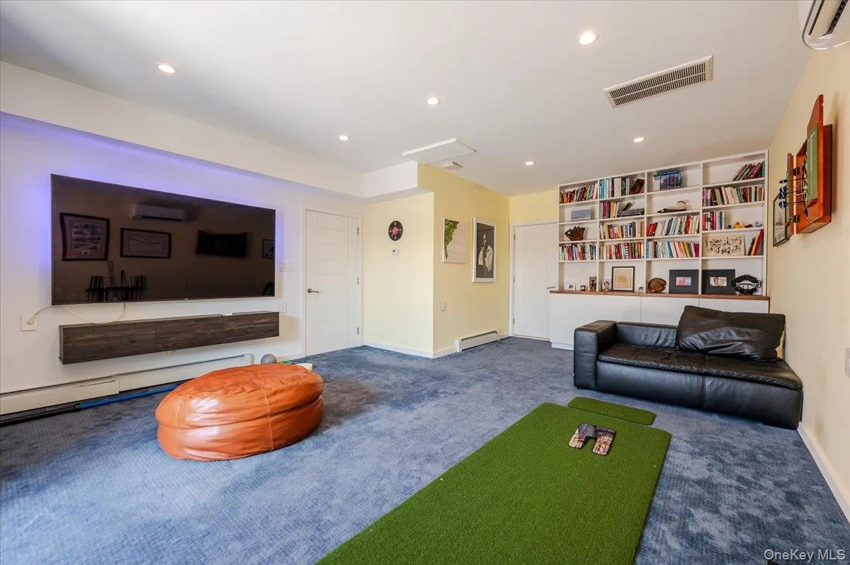 Living area with carpet flooring, recessed lighting, a wall mounted AC, and a baseboard radiator Living area with carpet flooring, recessed lighting, a wall mounted AC, and a baseboard radiator