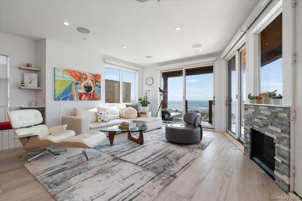 Living room featuring light wood-type flooring, recessed lighting, a water view, and a stone fireplace Living room featuring light wood-type flooring, recessed lighting, a water view, and a stone fireplace