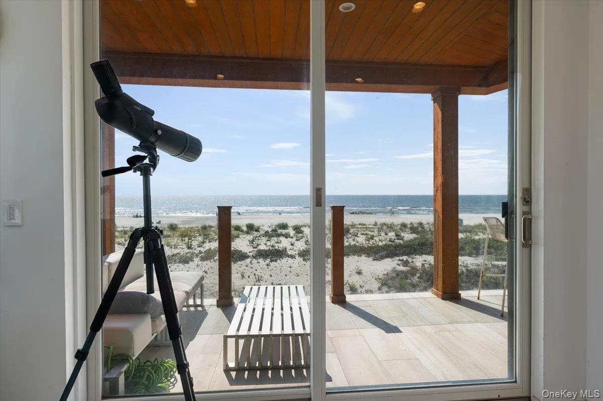 Entryway featuring plenty of natural light, view of water and beach, and wood ceiling Entryway featuring plenty of natural light, view of water and beach, and wood ceiling