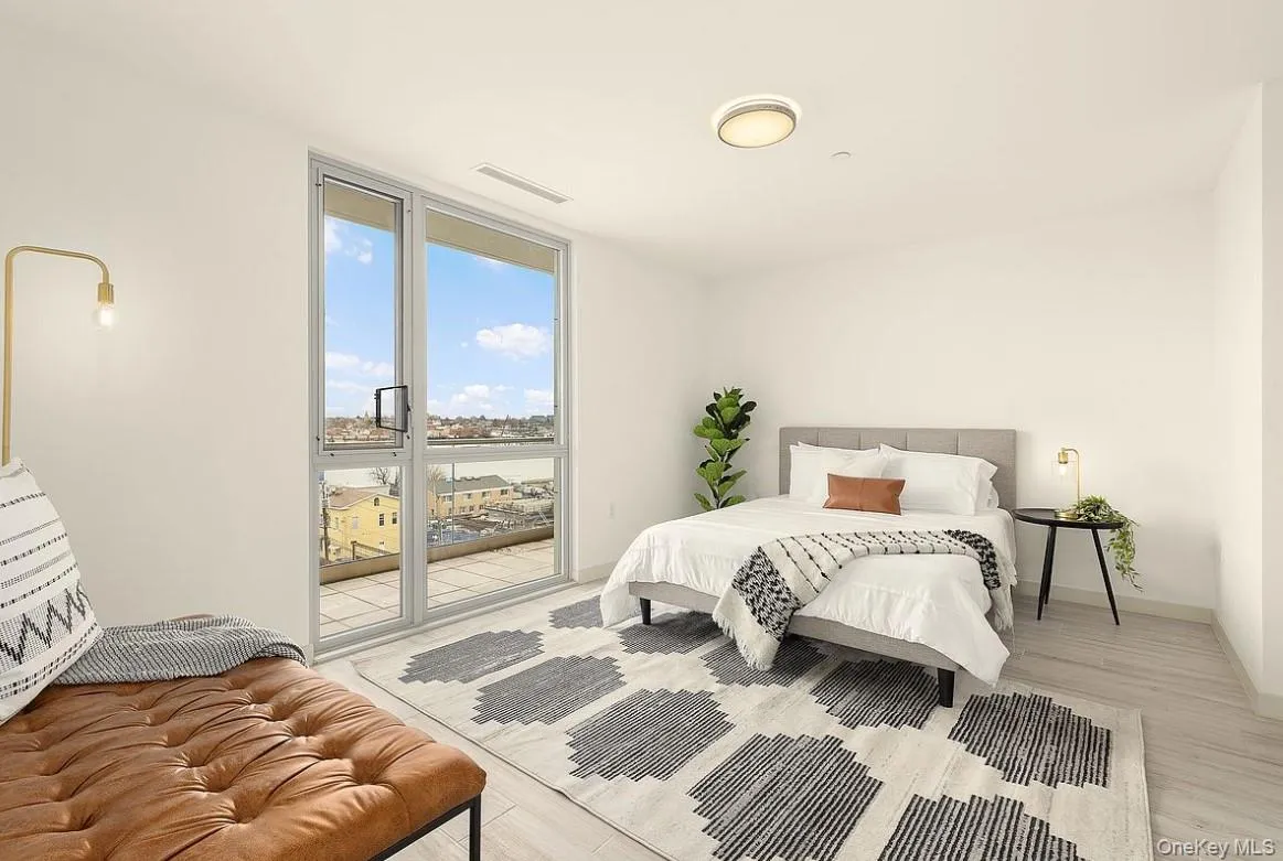 Bedroom with light wood-style flooring, a wall of windows, and access to exterior Bedroom with light wood-style flooring, a wall of windows, and access to exterior
