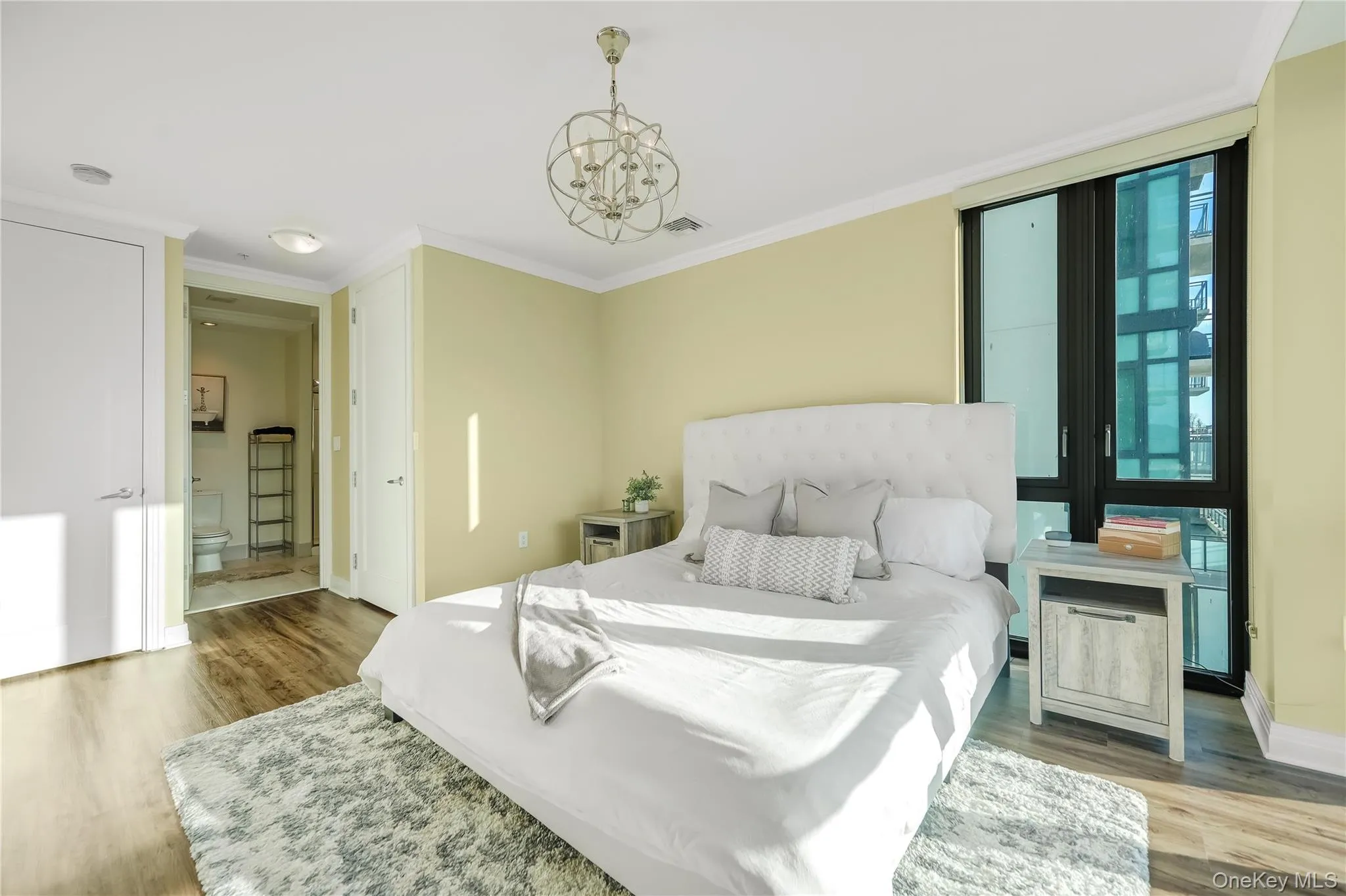 Bedroom featuring light wood finished floors, a chandelier, and crown molding Bedroom featuring light wood finished floors, a chandelier, and crown molding