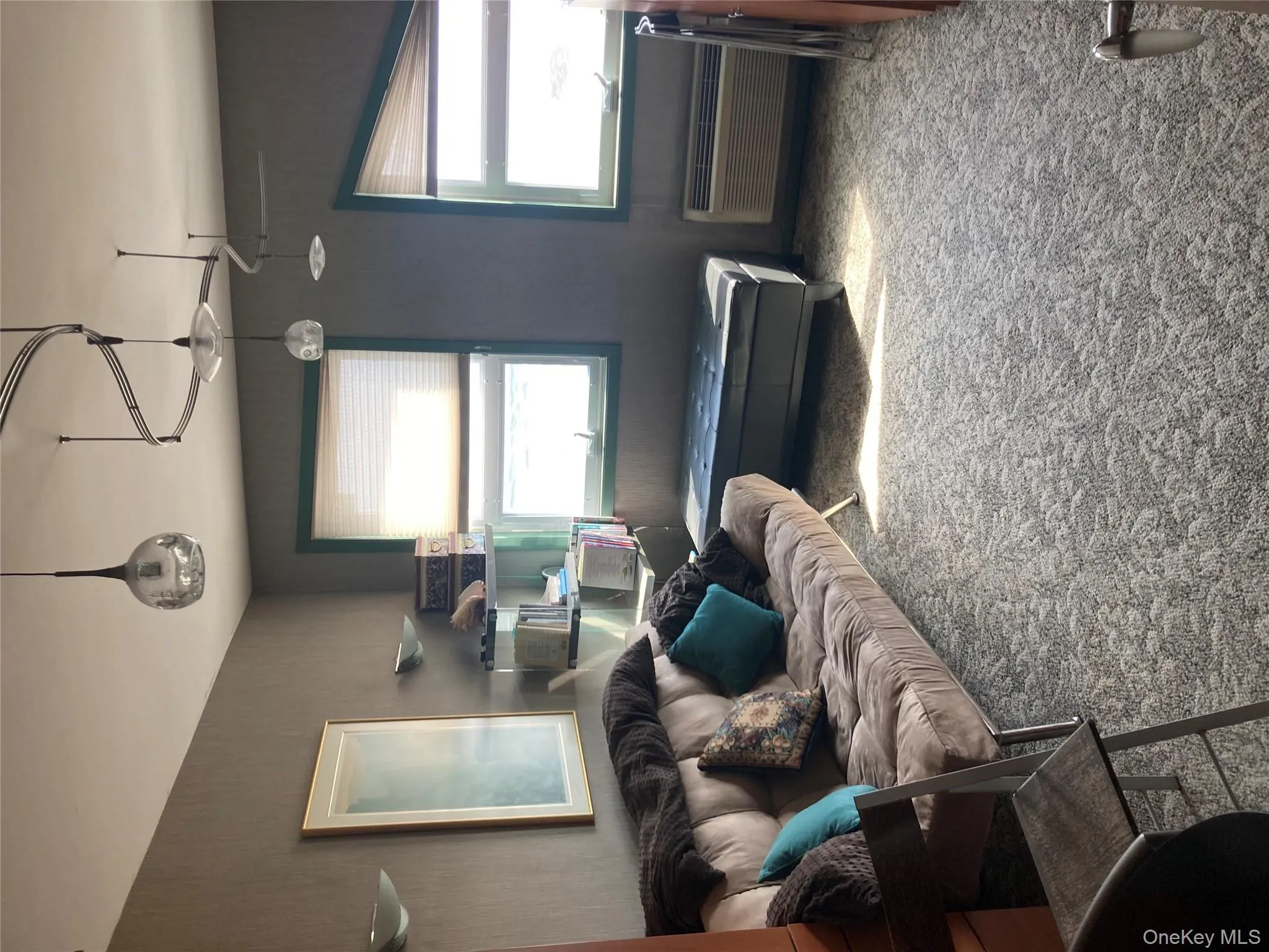 Carpeted living area featuring healthy amount of natural light and a wall mounted air conditioner Carpeted living area featuring healthy amount of natural light and a wall mounted air conditioner