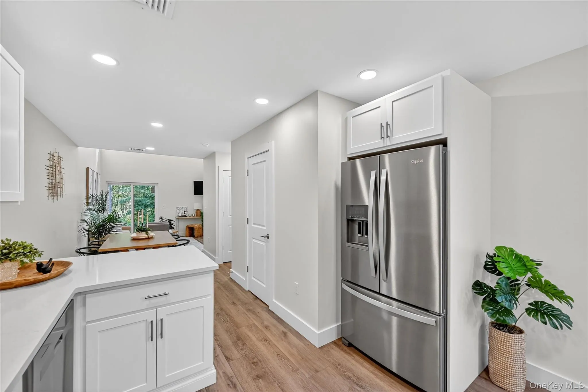 Kitchen featuring light countertops, stainless steel fridge, white cabinets, recessed lighting, and light wood-style flooring Kitchen featuring light countertops, stainless steel fridge, white cabinets, recessed lighting, and light wood-style flooring