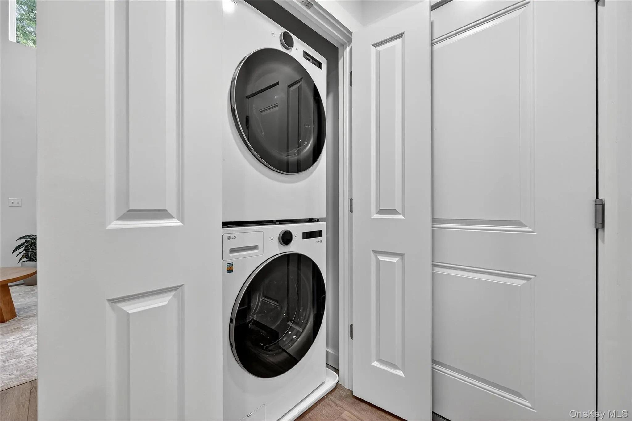 Laundry area featuring stacked washer / dryer and wood finished floors Laundry area featuring stacked washer / dryer and wood finished floors