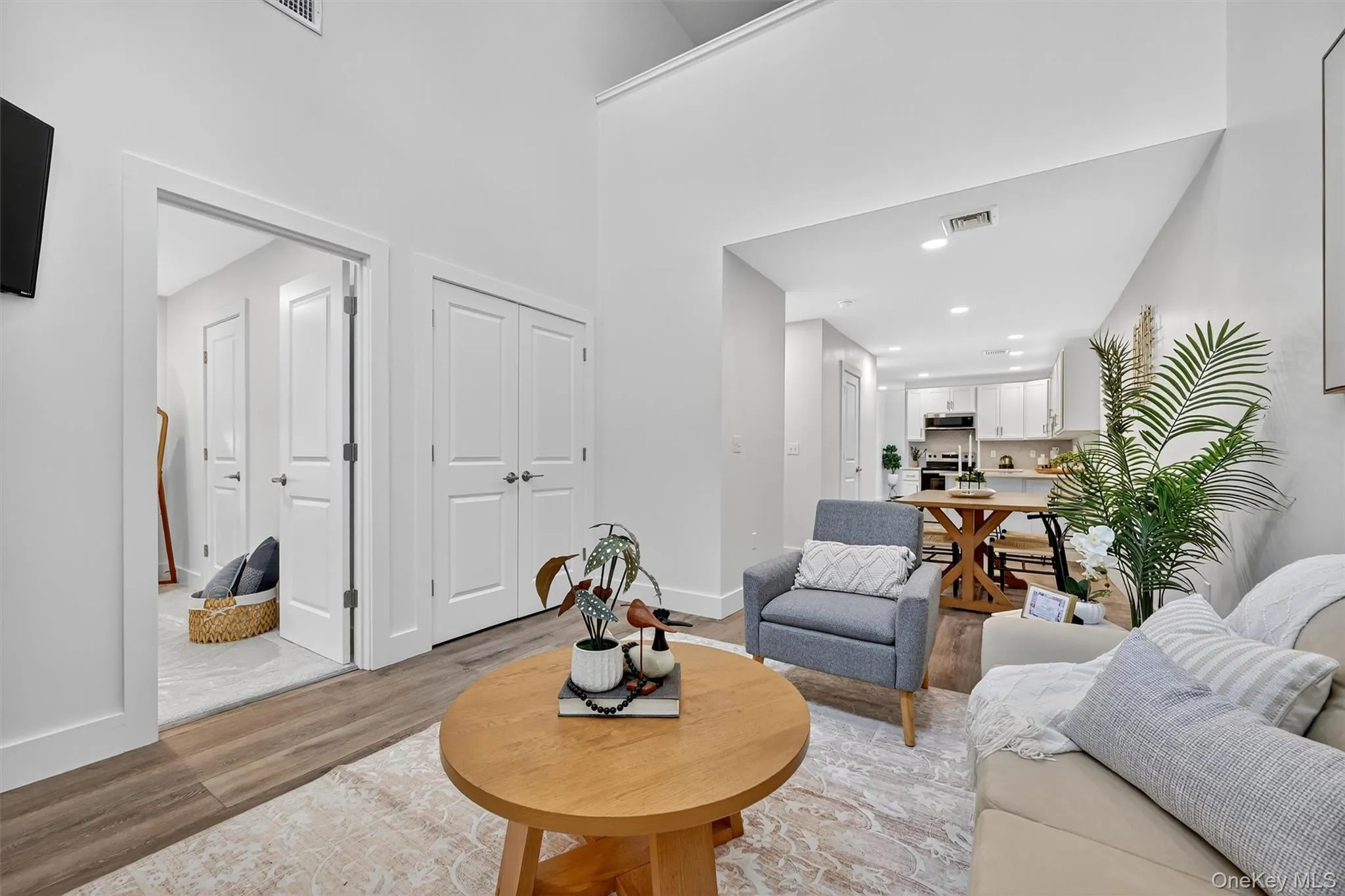 Living room with light wood-style floors, recessed lighting, and a high ceiling Living room with light wood-style floors, recessed lighting, and a high ceiling