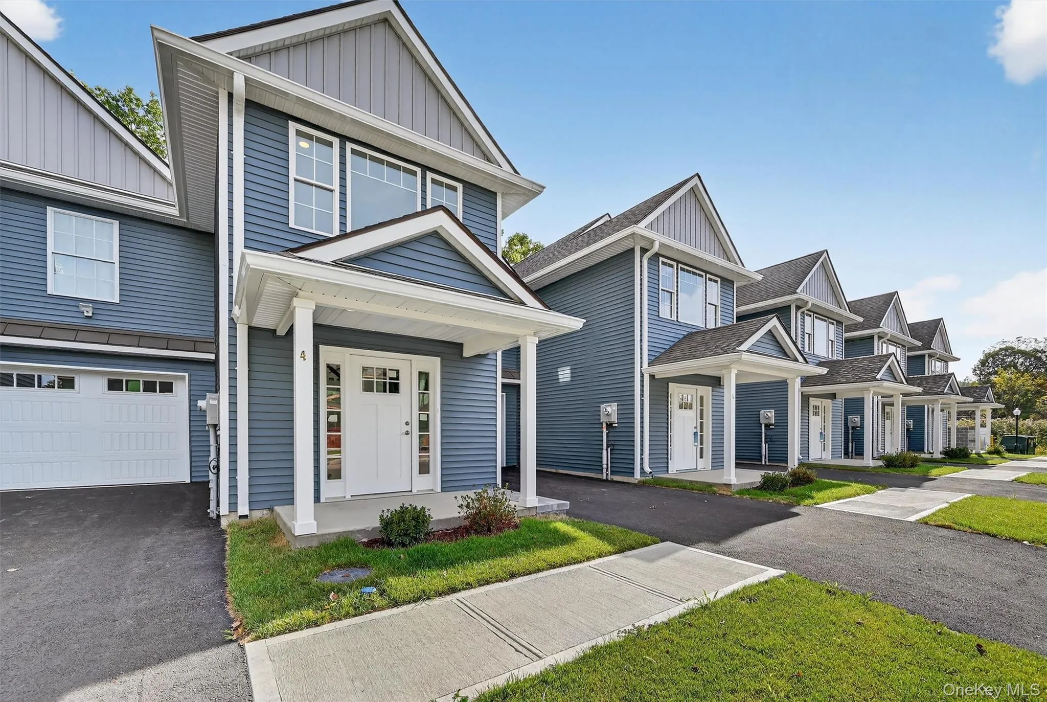 View of front of property featuring board and batten siding, covered porch, asphalt driveway, and an attached garage View of front of property featuring board and batten siding, covered porch, asphalt driveway, and an attached garage
