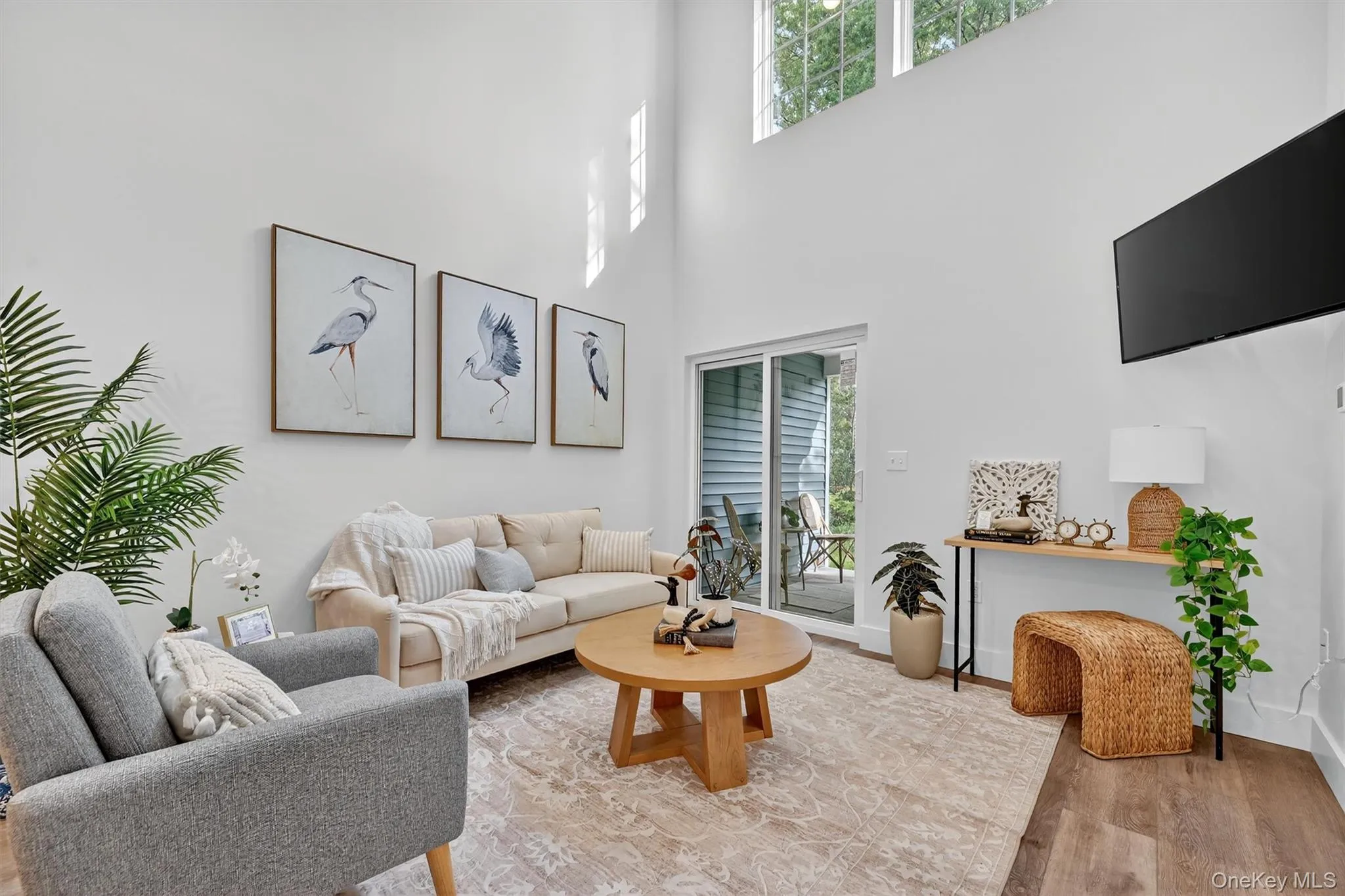 Living room featuring light wood finished floors and a towering ceiling Living room featuring light wood finished floors and a towering ceiling