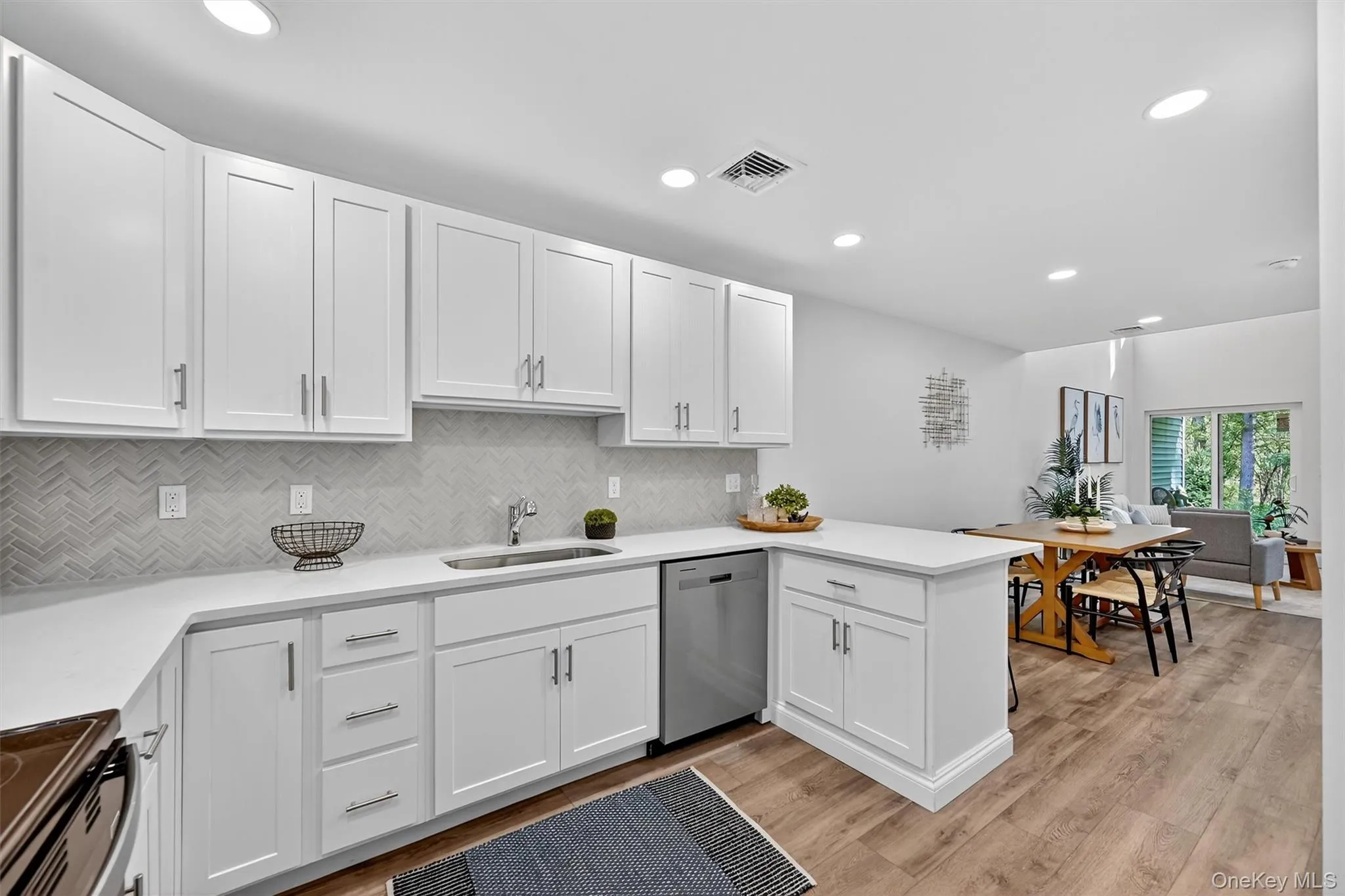 Kitchen with white cabinets, backsplash, dishwasher, black range with electric stovetop, and recessed lighting Kitchen with white cabinets, backsplash, dishwasher, black range with electric stovetop, and recessed lighting
