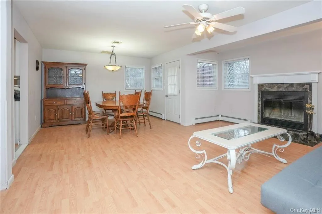 Dining room with light wood-type flooring, a high end fireplace, and a ceiling fan Dining room with light wood-type flooring, a high end fireplace, and a ceiling fan