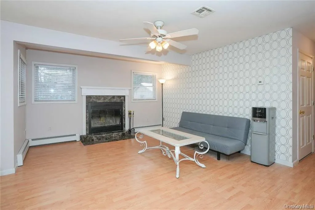 Sitting room with a high end fireplace, light wood-style flooring, wallpapered walls, healthy amount of natural light, and ceiling fan Sitting room with a high end fireplace, light wood-style flooring, wallpapered walls, healthy amount of natural light, and ceiling fan