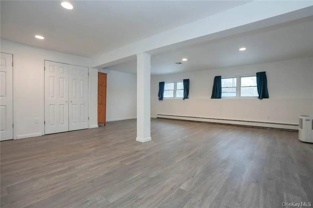 Basement featuring recessed lighting, wood finished floors, and a baseboard radiator Basement featuring recessed lighting, wood finished floors, and a baseboard radiator
