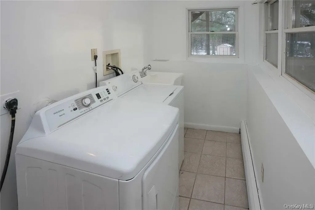 Laundry area featuring light tile patterned flooring, a baseboard heating unit, and washing machine and clothes dryer Laundry area featuring light tile patterned flooring, a baseboard heating unit, and washing machine and clothes dryer