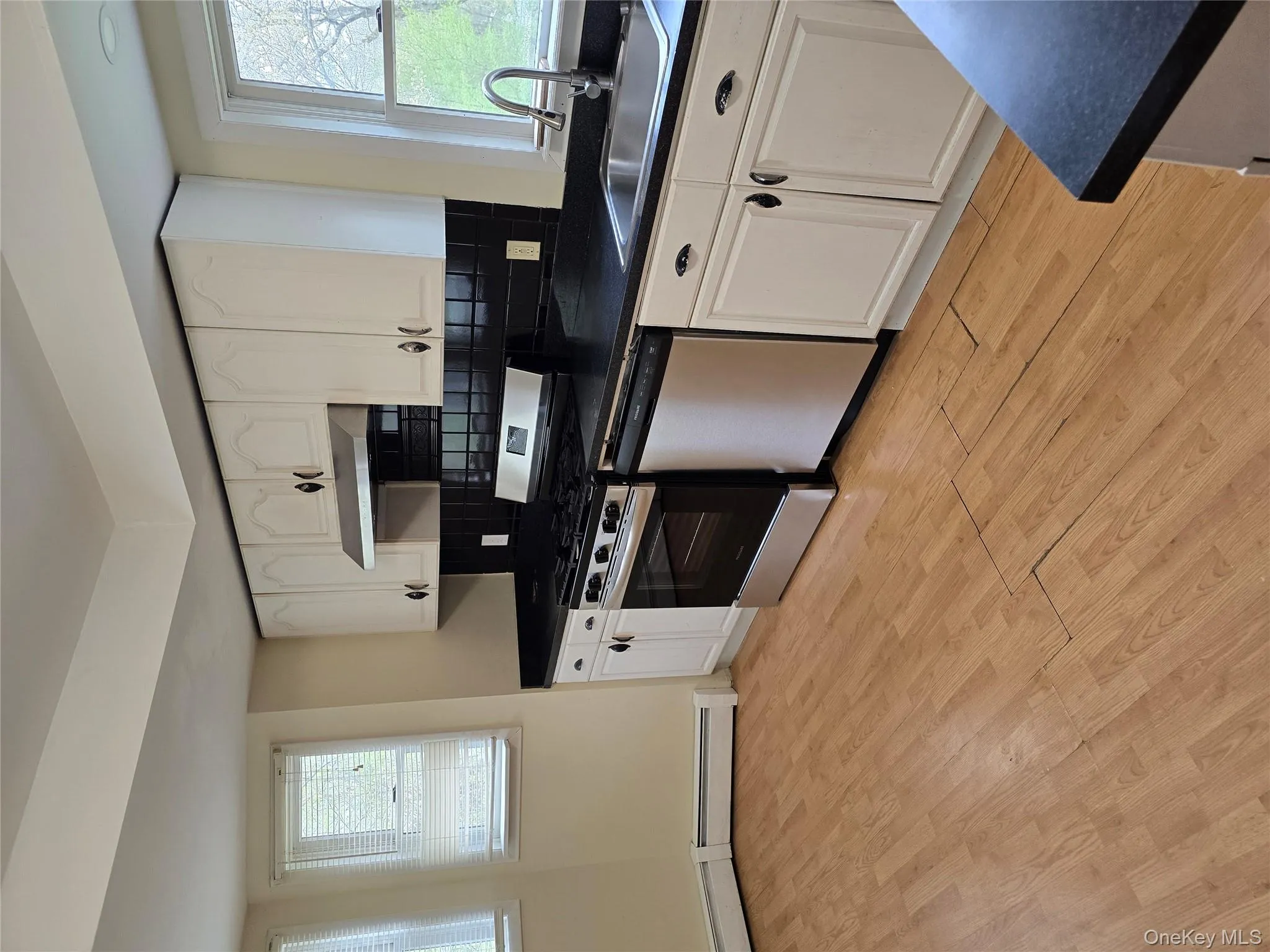 Kitchen with dark countertops, white cabinetry, appliances with stainless steel finishes, and decorative backsplash Kitchen with dark countertops, white cabinetry, appliances with stainless steel finishes, and decorative backsplash