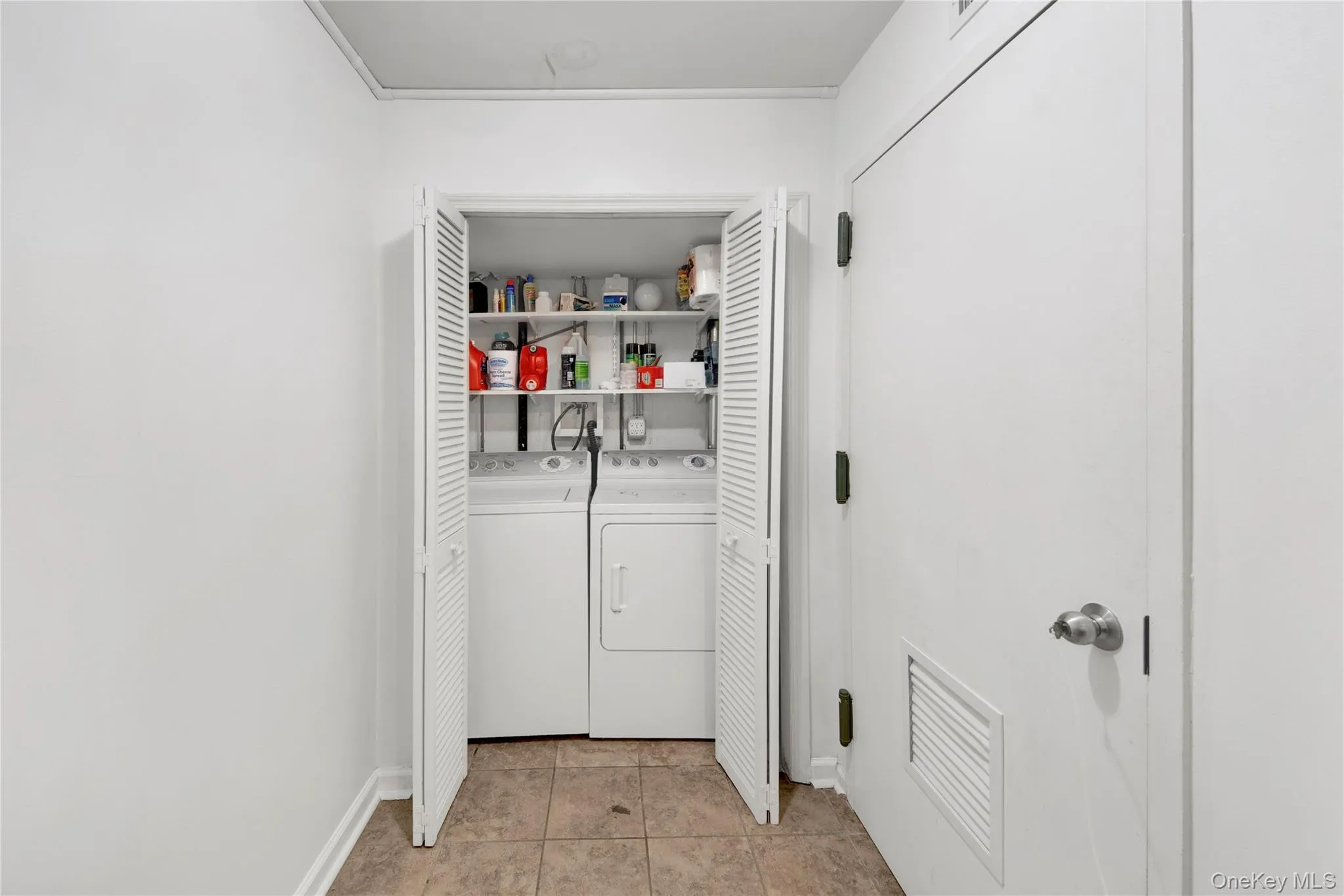 Washroom with light tile patterned flooring and independent washer and dryer Washroom with light tile patterned flooring and independent washer and dryer