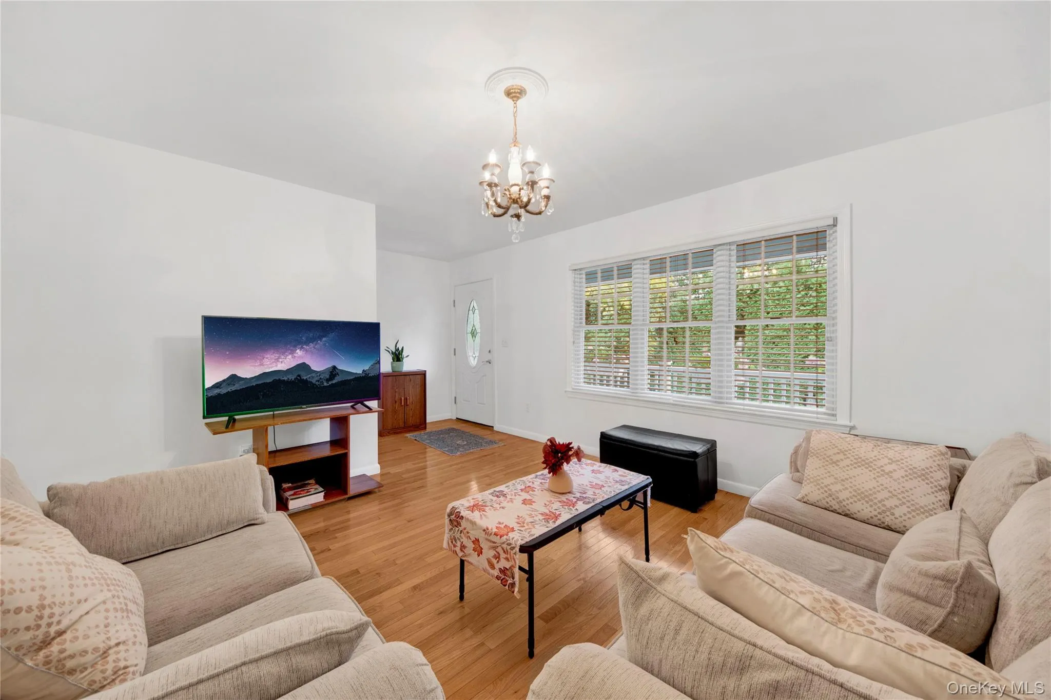 Living room featuring light wood-style flooring and a chandelier Living room featuring light wood-style flooring and a chandelier