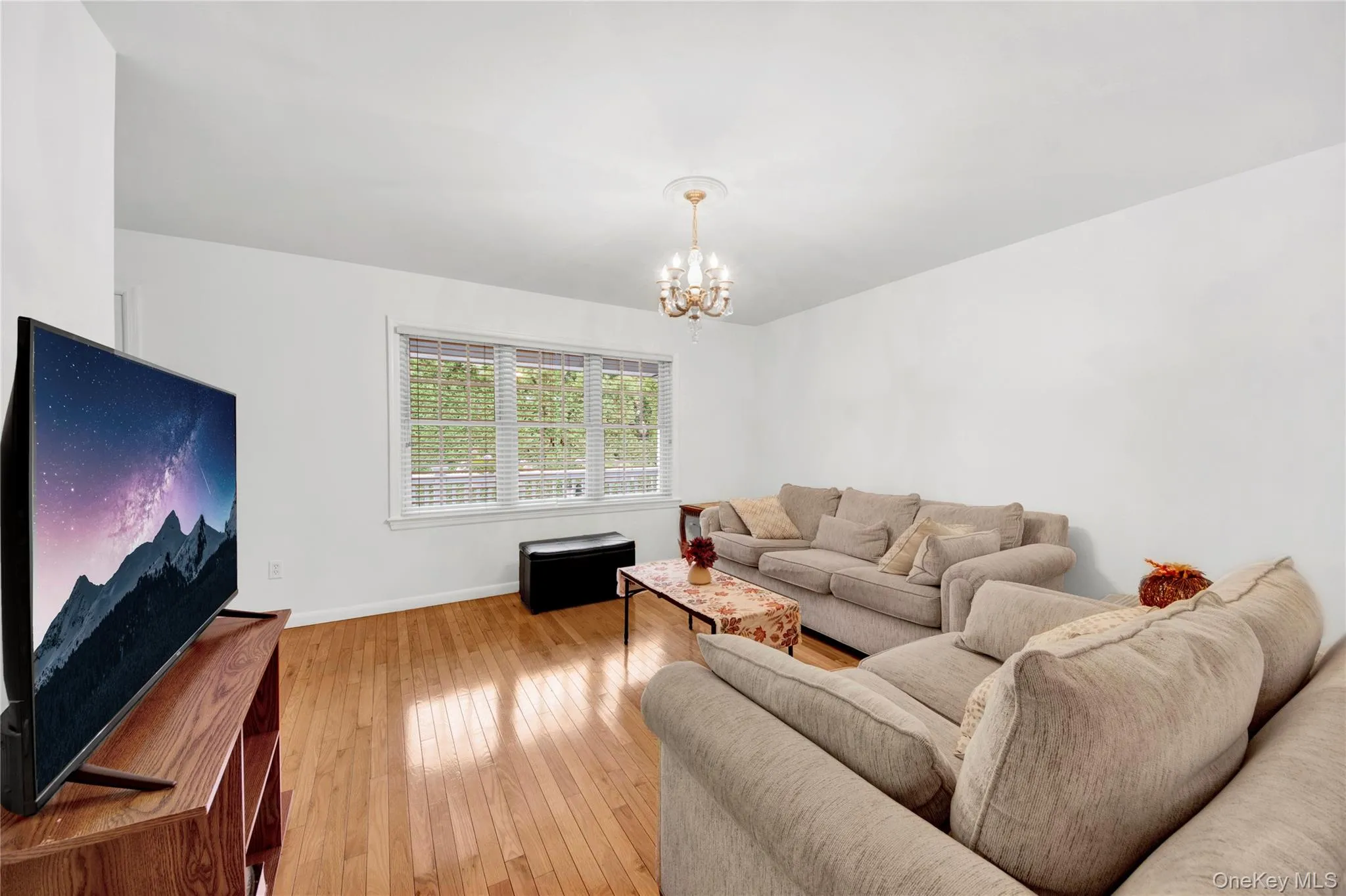 Living area with a chandelier and light wood finished floors Living area with a chandelier and light wood finished floors