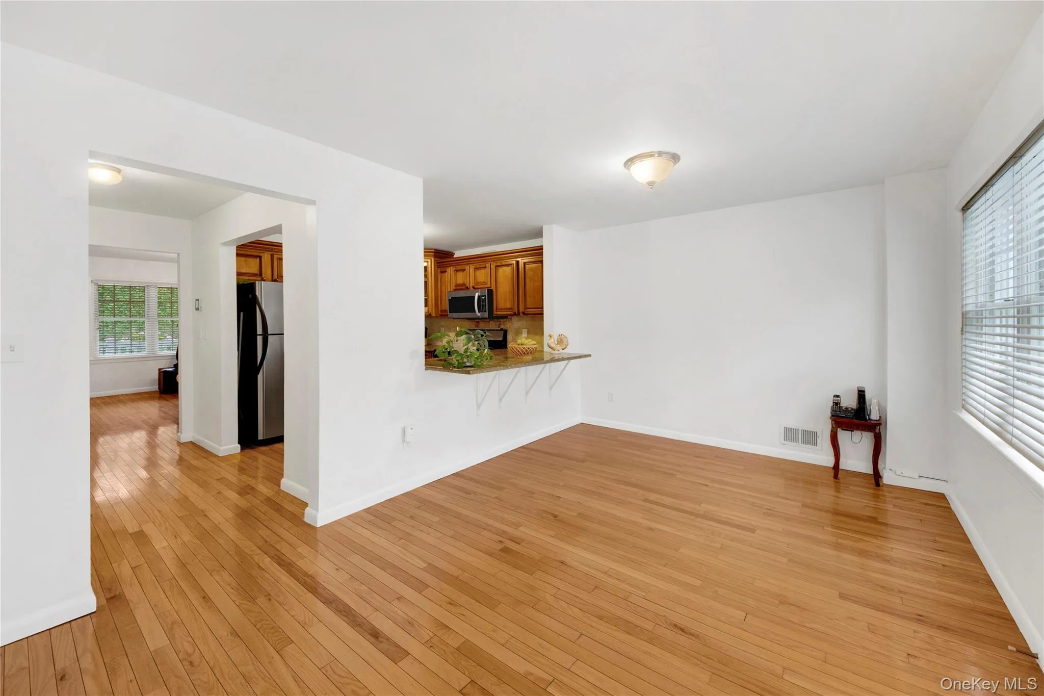 Unfurnished living room with light wood-type flooring and baseboards Unfurnished living room with light wood-type flooring and baseboards