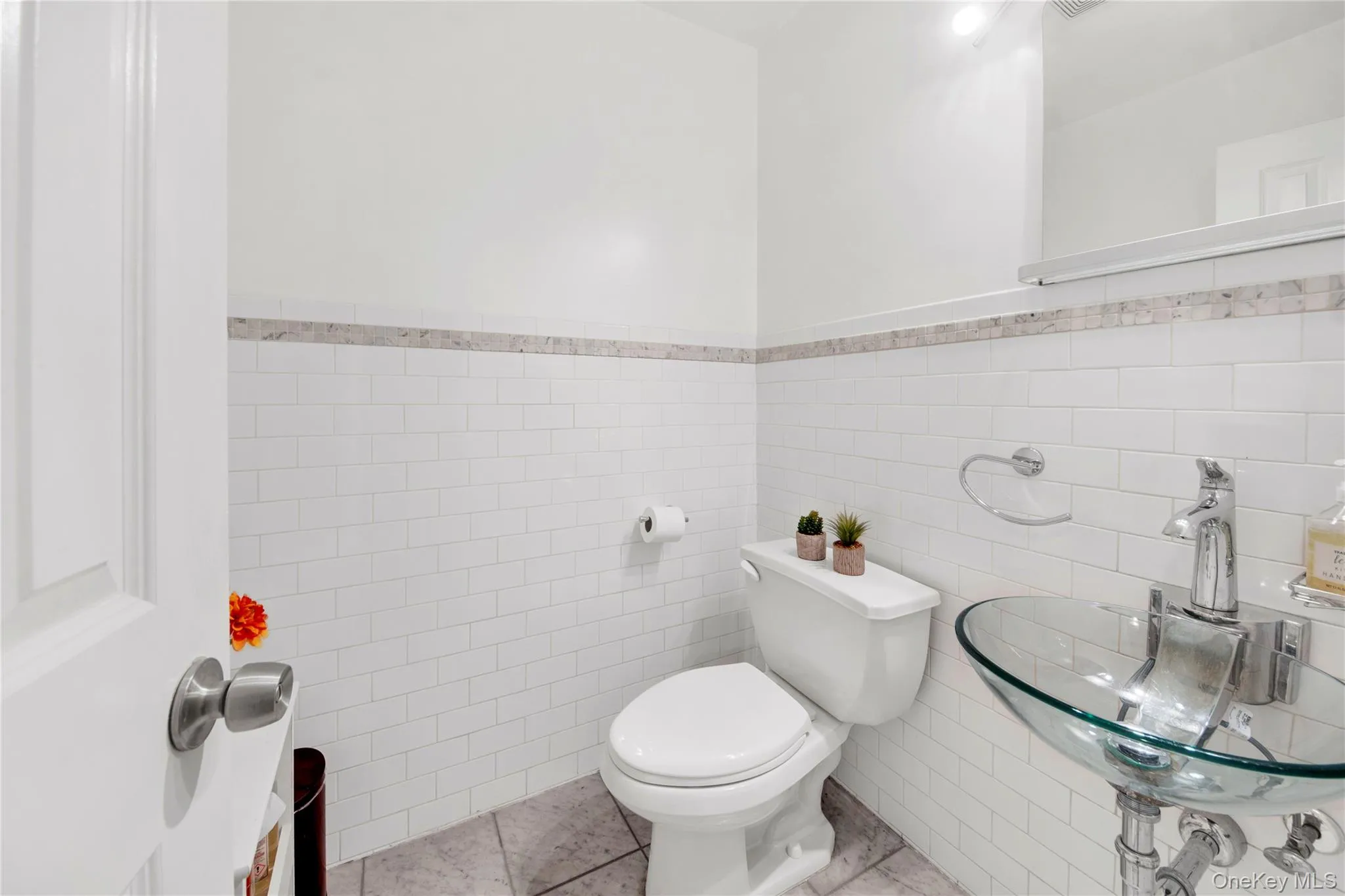 Half bath featuring tile walls, wainscoting, and tile patterned flooring Half bath featuring tile walls, wainscoting, and tile patterned flooring