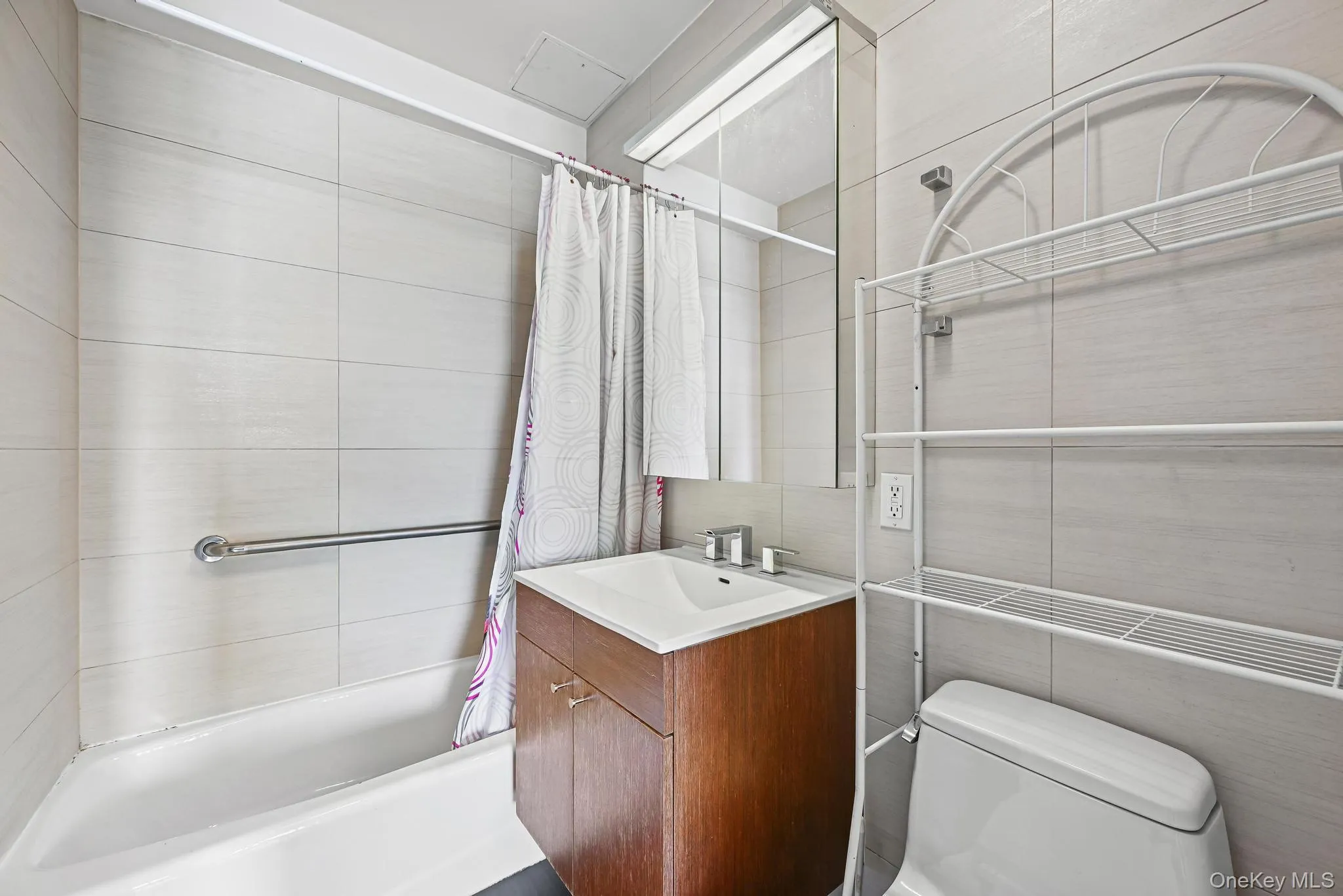 Bathroom featuring tile walls, vanity, and shower / bathtub combination with curtain Bathroom featuring tile walls, vanity, and shower / bathtub combination with curtain